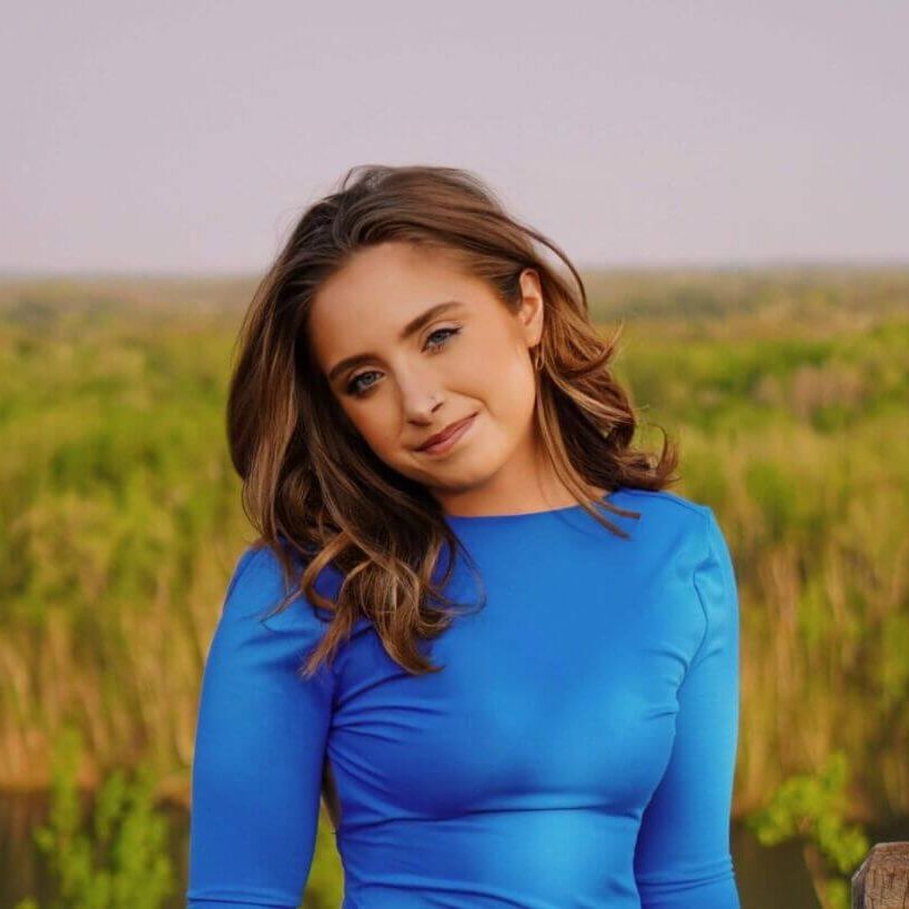 Headshot of Sam in a field at sunset