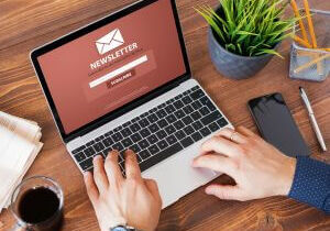 Hands typing on a laptop showing an email newsletter screen